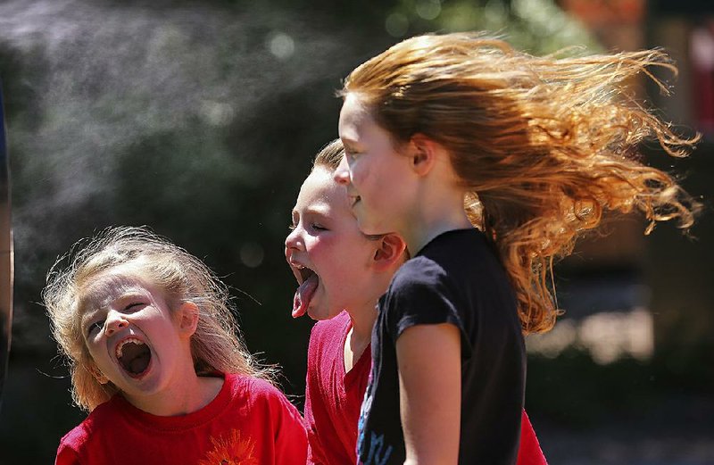 Khloe Batz (from left), Clara Bruner and Layna Bruner, all from Blevins, enjoy a blast of wet, cold air from a fan during a visit to the Little Rock Zoo on Thursday. The zoo is hosting Red, White & Zoo Days this Memorial Day weekend, offering half-priced admission to active or veteran military members and their families. 