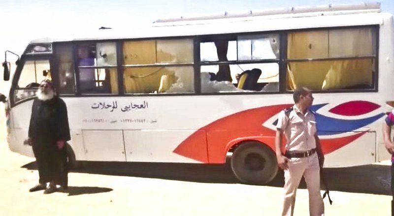 This image released by the Minya governorate media office shows a policeman and a priest next to a bus after gunmen stormed the bus in Minya, Egypt, on Friday, May 26, 2017. 