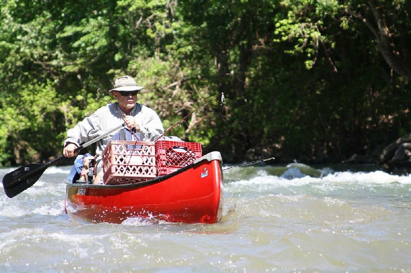 Rusty Pruitt of Bryant sails through a rapid Monday while fishing on Crooked Creek in Marion County, part of an annual float trip. 