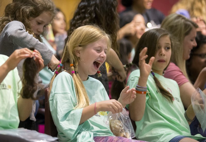 NWA Democrat-Gazette/JASON IVESTER Mia Hernandez, a third-grader, reacts as she gets her hair cut during a Pantene Beautiful Lengths event at Reagan Elementary School in Rogers.