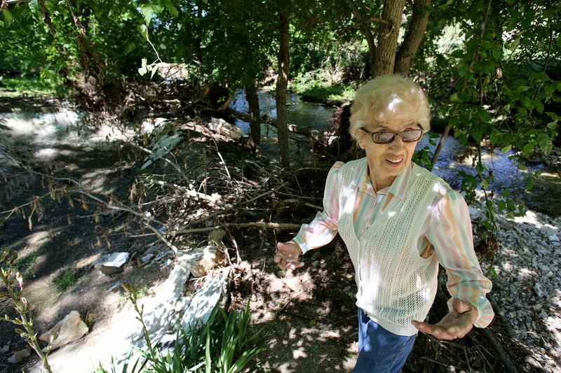 NWA Democrat-Gazette/DAVID GOTTSCHALK Elfi Davis surveys Thursday the damage and debris left behind by the flooding of a creek next her home at 23000 Salem Springs Road in rural Washington County. The series of recent rain have flooded the creek eroding away the stream bank and flooding her property.