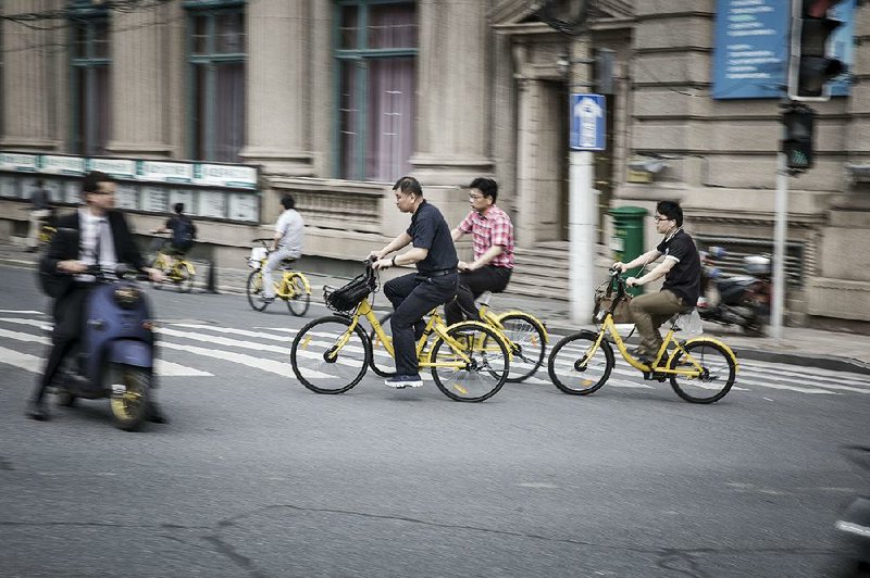 Commuters ride Ofo Inc. bicycles along a sidewalk in Shanghai last week. 