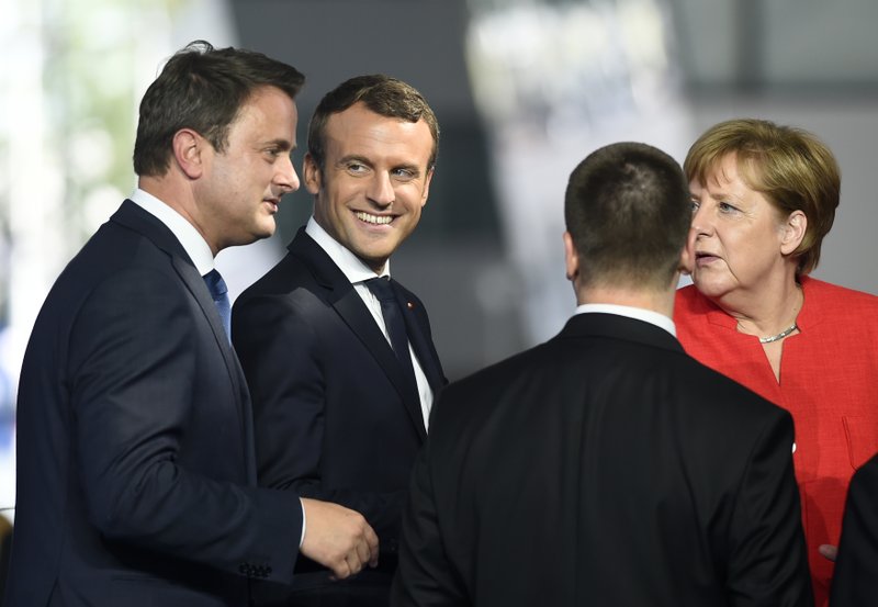 Luxembourg's Prime Minister Xavier Bettel, left, talks with French President Emmanuel Macron, second left, and German Chancellor Angela Merkel, right as NATO member leaders gather to pose for a group photo, prior to the start of their summit in Brussels, Belgium, Thursday, May 25, 2017.