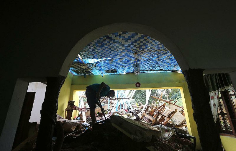 A Sri Lankan landslide survivor salvages belongings Monday from a damaged house in Kiribathgala. Severe weather across the country caused flooding and landslides that have killed dozens of people. 