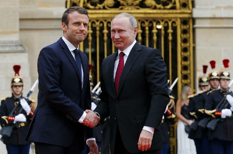 French President Emmanuel Macron (left) shakes hands with Russian President Vladimir Putin on Monday at the Palace of Versailles near Paris. 