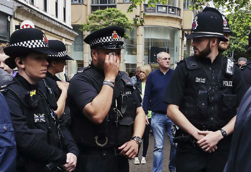 A police officer in Manchester, England, wipes away tears Monday as he looks at !owers and tributes left in St. Ann’s Square in memory of the victims of last week’s bombing. 