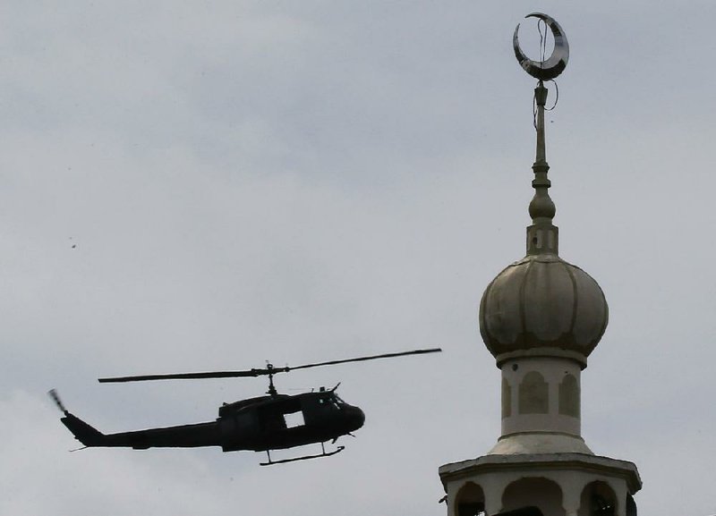 A Philippine military helicopter hovers Monday near a mosque as government troops battle with militants in Marawi city.