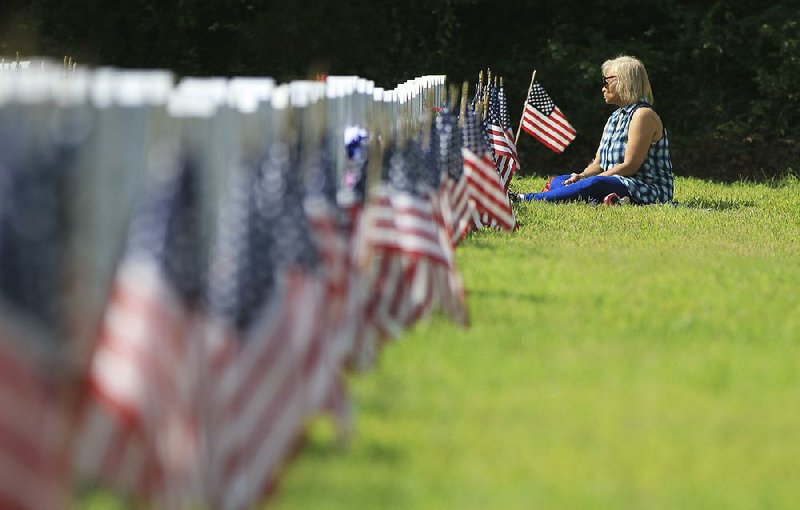 Riley Miller sits Monday morning at the grave of her husband, Edward Miller Jr., during the Memorial Day program at the Arkansas State Veterans Cemetery in North Little Rock. Edward Miller was in the U.S. Air Force and served in Vietnam and the Persian Gulf.  