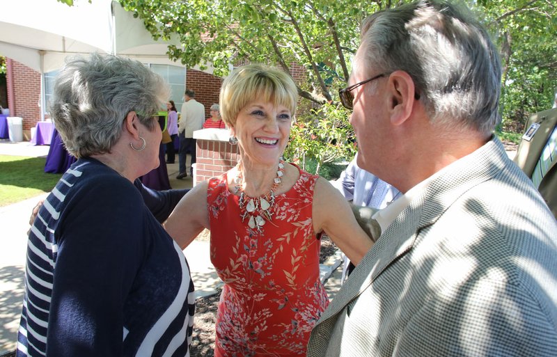 NWA Democrat-Gazette/DAVID GOTTSCHALK Barbara Prichard (center), director of Gifted and Talented and Advanced Placement for Fayetteville Public Schools, is greeted Thursday by Jane (left) and David Gearhart, former chancellor for the University of Arkansas, at a reception in the courtyard of the McClinton Administration Building in Fayetteville. Prichard is retiring after 34 years in education. story.lead_photo.caption
