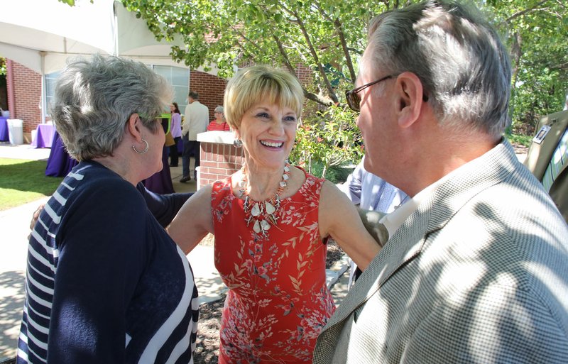 NWA Democrat-Gazette/DAVID GOTTSCHALK Barbara Prichard (center), director of Gifted and Talented and Advanced Placement for Fayetteville Public Schools, is greeted Thursday by Jane (left) and David Gearhart, former chancellor for the University of Arkansas, at a reception in the courtyard of the McClinton Administration Building in Fayetteville. Prichard is retiring after 34 years in education.