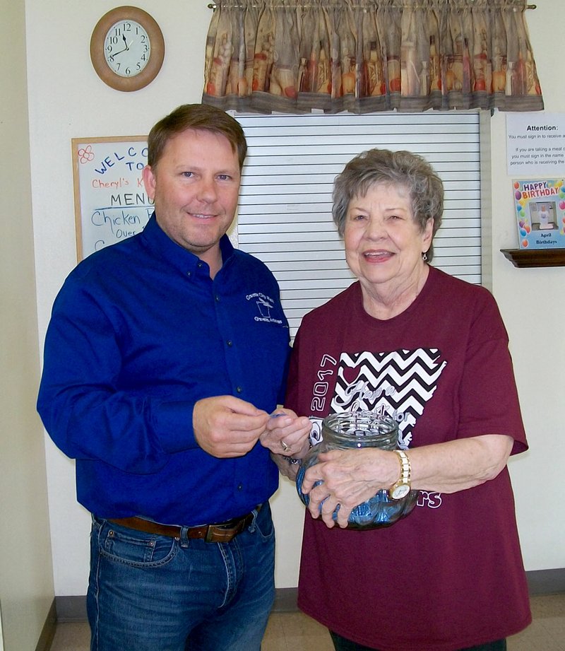 Photo by Melissa Steele Gravette mayor Kurt Maddox pulled a name from the jar to determine the lucky person who would win the drawing for a grocery cart overflowing with food items. Maddox and Billy V. Hall Senior Center director Mary Kay Kelley were pleased to discover that the winner was a senior center employee. He promptly delivered his winnings to a needy senior center patron.