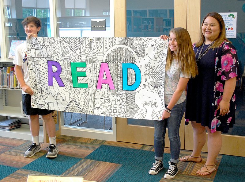 Janelle Jessen/Herald-Leader Sixth-grade Discovery students Ashley Drake and Andrew Pilcher, along with their teacher Stephanie Harper, presented a portable mural to the Siloam Springs Public Library on Tuesday. Not pictured is Riley Bell, who also helped with the project. The mural was one of nine community projects completed by sixth-grade Discovery students.