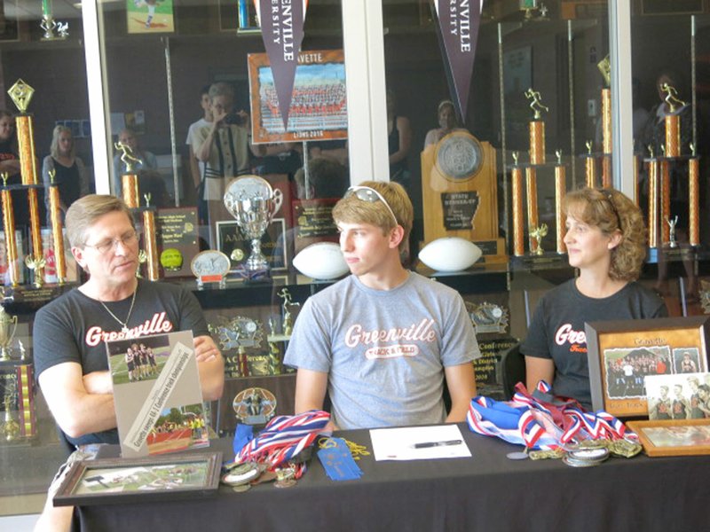 Photo by Susan Holland Alex Fink (center), a 2017 graduate of Gravette High School, shared a moment of reflection with his parents, Bryan and Lucretia Fink, before signing Thursday, May 25, to run track at Greenville University in Greenville, Ill.
