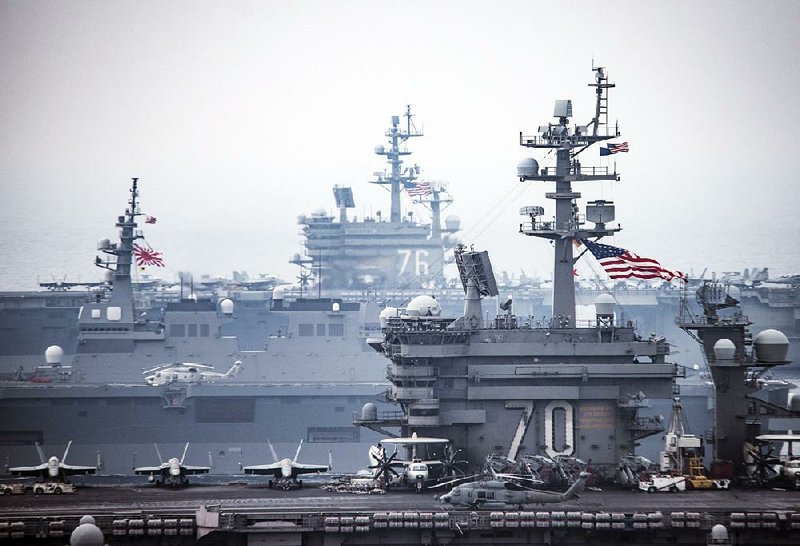 Aircraft sit on the flight deck of the USS Carl Vinson on Thursday in the western Paciÿc region where tensions with North Korea are high. The USS Ronald Reagan (rear) and Japan’s Hyuga (left) are in the background.  