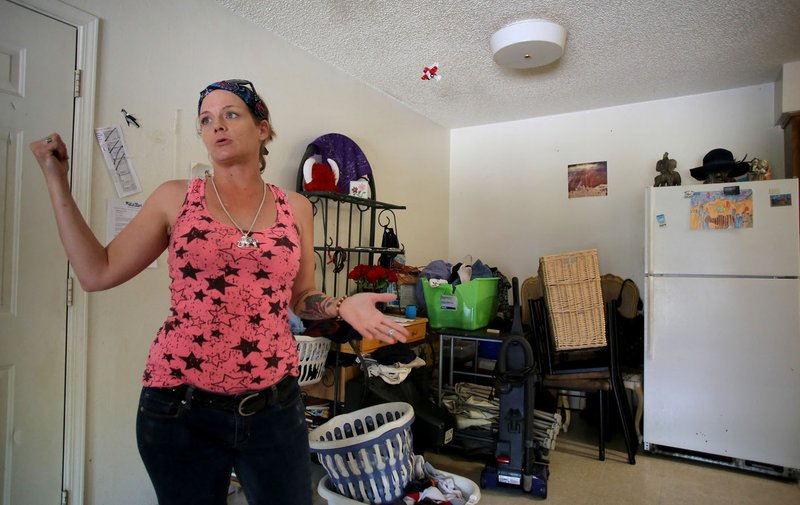 NWA Democrat-Gazette/DAVID GOTTSCHALK Christina Annis, a three-year resident at Southmont Apartment, speaks Monday about the bullet holes in her living room and kitchen walls from gunfire outside her apartment from overnight gunfire the first part of May in Fayetteville.