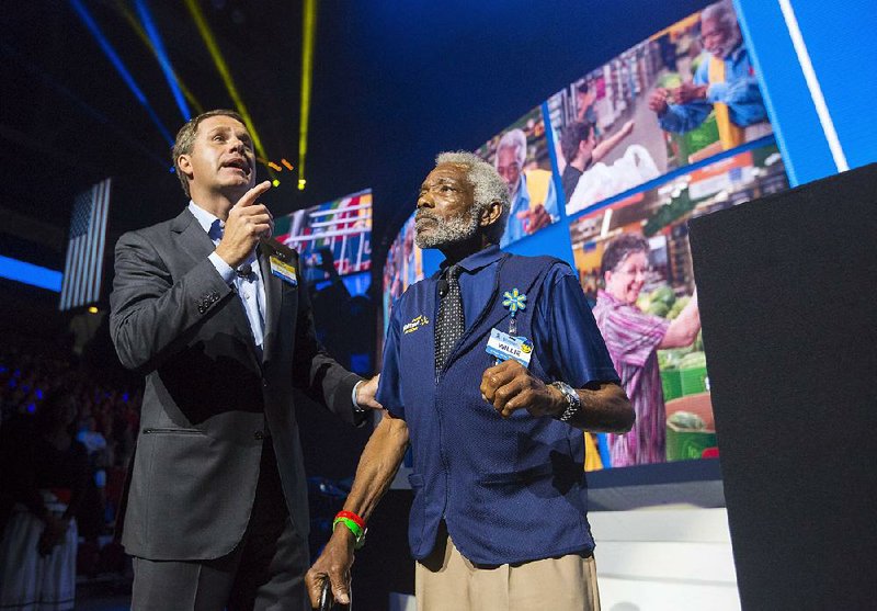 Wal-Mart President and CEO Doug McMillon talks with employee Willie Perkins during the company’s shareholder meeting Friday at Bud Walton Arena in Fayetteville.