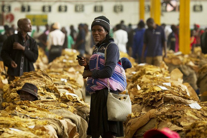 A woman, with her handbag and her baby, waits in mid-May to sell her tobacco crop at the Tobacco Sales Floor in Harare, Zimbabwe.