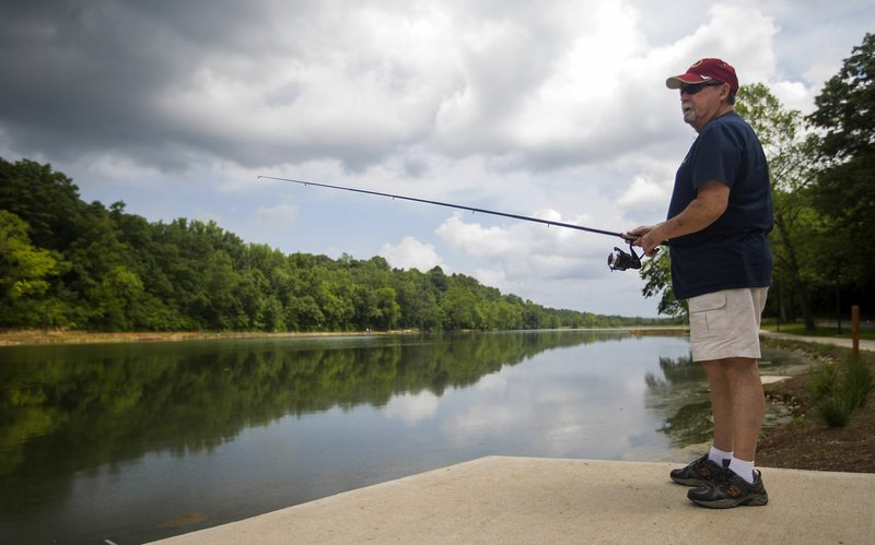 Joel Ray of Fayetteville fishes Thursday at Lake Atalanta in Rogers. Sections of the park are being reopened to the public following flood damage in April.