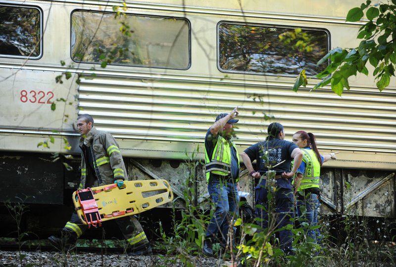 Ron Sparks (center), chief of the Arkansas Missouri Railroad police, speaks to members of his staff as a firefighter carries a piece of emergency equipment after an accident involving an Arkansas &amp; Missouri Railroad train on Oct. 16, 2014, south of West Fork.