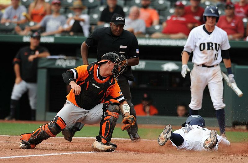 Oral Roberts third baseman Cal Hernandez (right) slides in safely at home ahead of a tag by Oklahoma State catcher Colin Simpson on Saturday during the third inning of the Golden Eagles’ 14-6 victory over the Cowboys at Baum Stadium in Fayetteville.