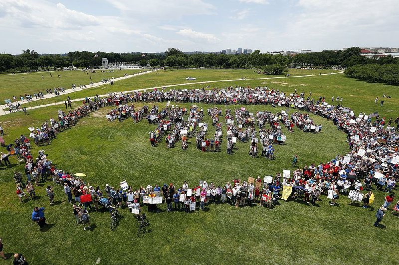 Protesters surround a group standing in a formation of letters that spell out “impeach Trump” on the National Mall in Washington during a rally Saturday against President Donald Trump and his policies. 