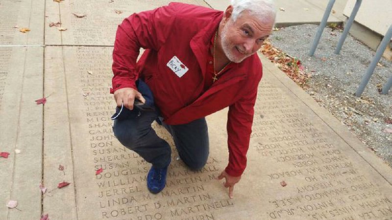 Ricardo Martinelli, who served as president of Panama for five years, kneels at the spot on the University of Arkansas, Fayetteville campus Senior Walk that bears his name as a graduate in this undated photo. 
