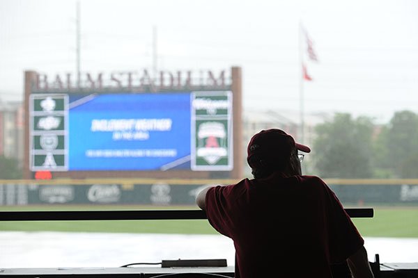 A fan sits in the stands at Baum Stadium during a rain delay prior to an NCAA Tournament game between Oral Roberts and Oklahoma State on Saturday, June 3, 2017, in Fayetteville. 