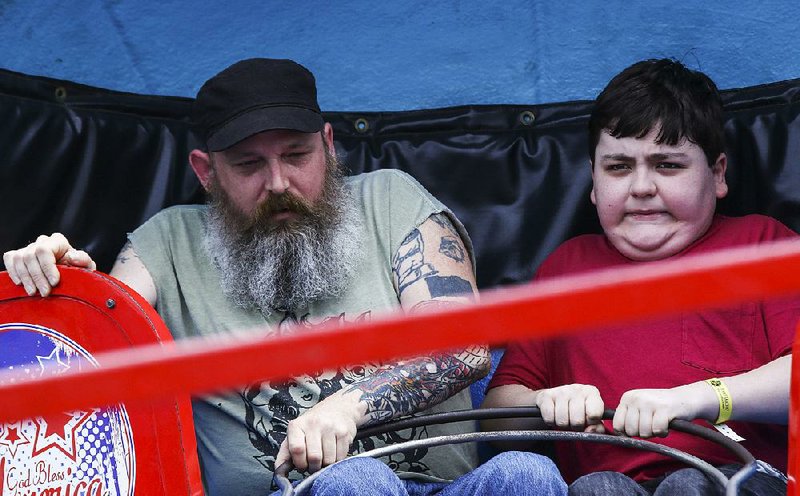 Michael Birch and his son Joseph, 12, both of Little Rock, feel the effects of the Tilt-a-Whirl during Riverfest in Little Rock on Sunday.