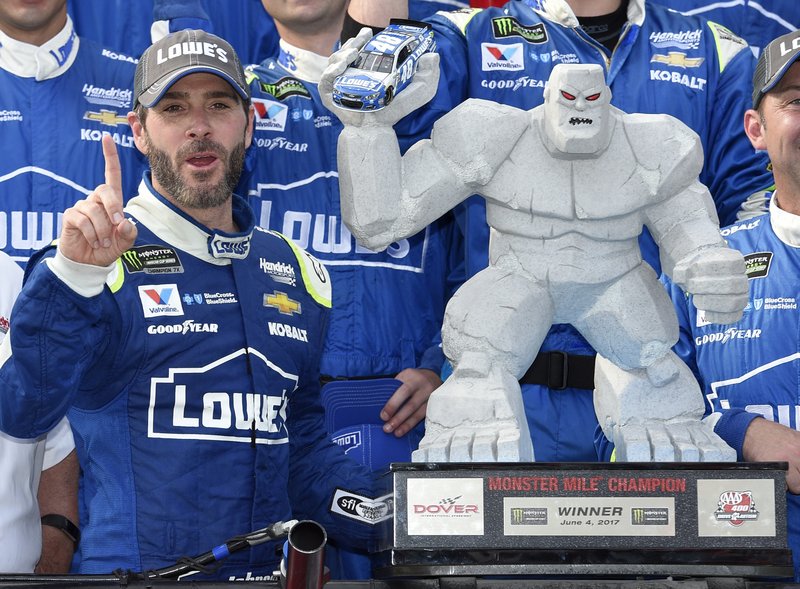 Jimmie Johnson, left, poses with the trophy in Victory Lane after he won a NASCAR Cup series auto race, Sunday, June 4, 2017, at Dover International Speedway in Dover, Del. 