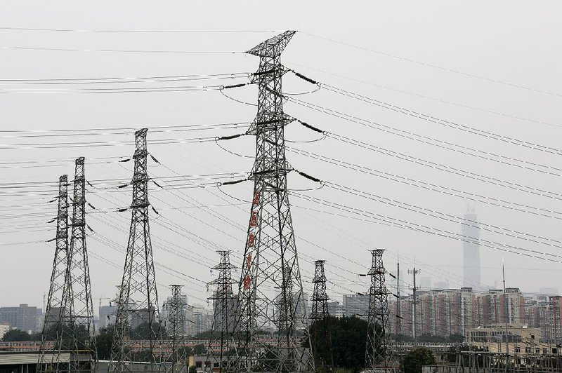 Electricity transmission towers stand near office and residential buildings shrouded by smog in Beijing on Monday. An increasing amount of energy from renewable sources is going unused in China because of difficulty integrating it into the power grid and a preference for coal-fired power plants in some provinces.