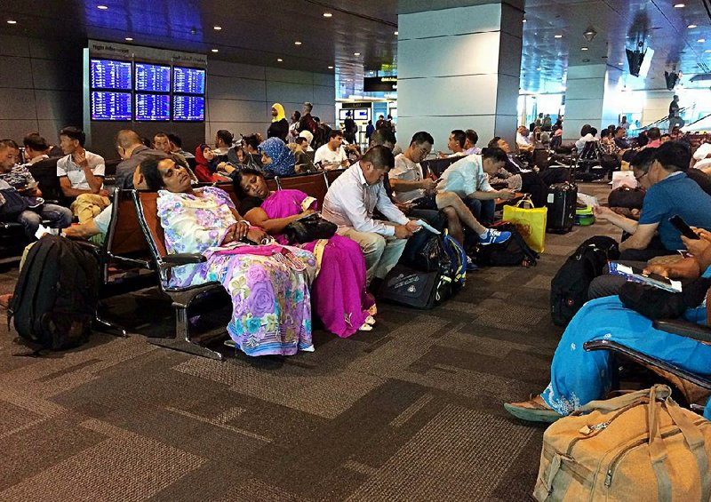 Stranded travelers sit and wait Tuesday at Hamad International Airport in Doha, Qatar. Flights were canceled after Qatar’s Persian Gulf neighbors and other Arab countries cut diplomatic ties. 