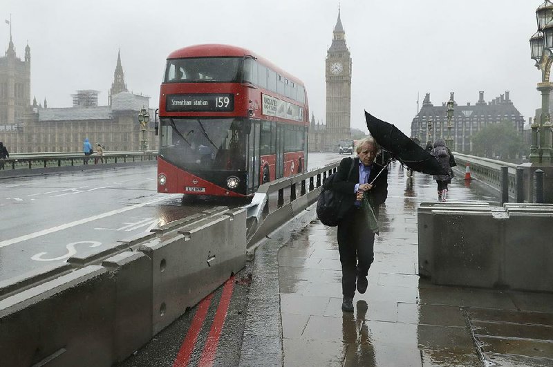 A pedestrian walks Tuesday past newly installed barriers on Westminster Bridge in London. The barriers are a security measure to help stop vehicles from veering onto the pedestrian part of London’s bridges. 