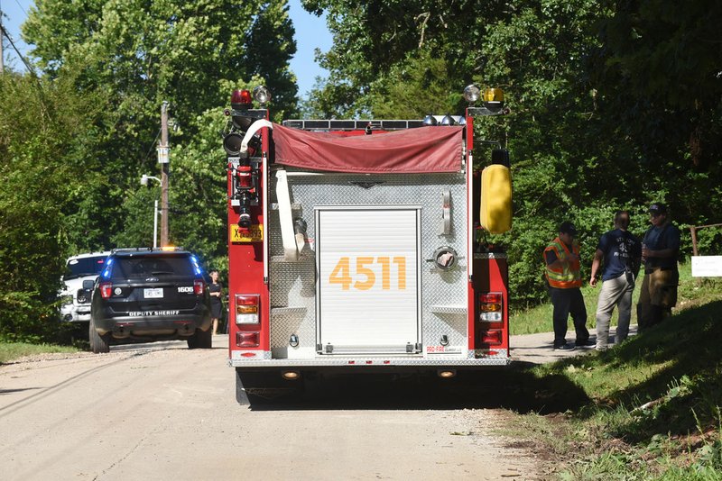 NWA Democrat-Gazette/FLIP PUTTHOFF Fire and law enforcement personnel work Tuesday along Canal Street in the Monte Ne community after a Benton County street sweeper hit a home. Two people were taken to a hospital, said Channing Barker, Road Department spokeswoman.