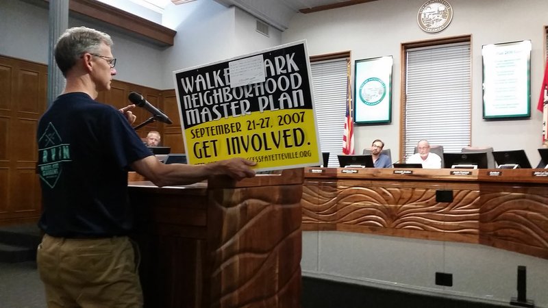  Resident Alan Ostner holds a sign depicting the 2007 campaign to develop a Walker Park neighborhood plan during a Fayetteville City Council meeting held Tuesday. Ostner encouraged council members to remember the original intent of the neighborhood plan when considering a rezoning in the area.