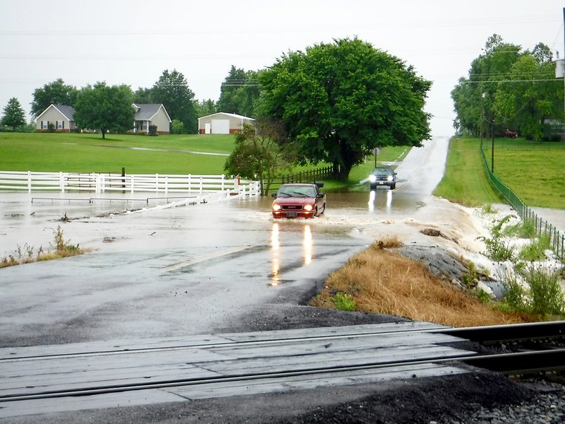 Floodwaters rushed across Pioneer Lane, south of the railroad, again on Sunday afternoon after heavy rains fell in the Gentry area.