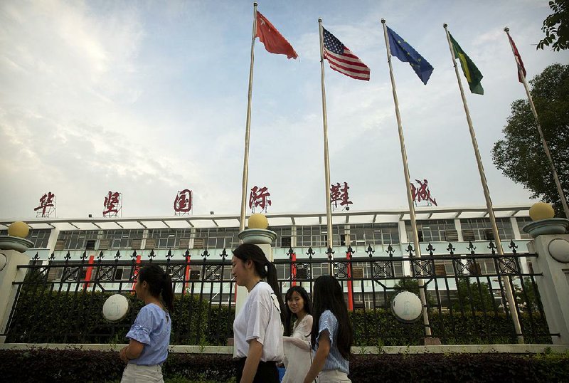 The flags of China, the United States and other nations fly Tuesday at a Huajian Group shoe factory in Ganzhou in southern China’s Jiangxi province. The Huajian Group made shoes for the Ivanka Trump fashion brand.