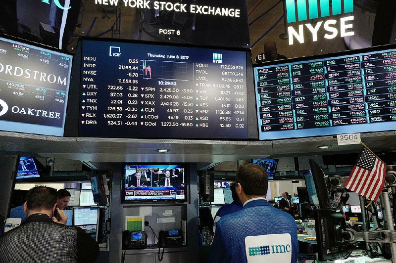 Traders at the New York Stock Exchange watch former FBI Director James Comey on a television monitor Thursday as he testified before a congressional committee in Washington. Comey’s testimony had little effect on the financial markets, but the Nasdaq composite index inched up to another record high.