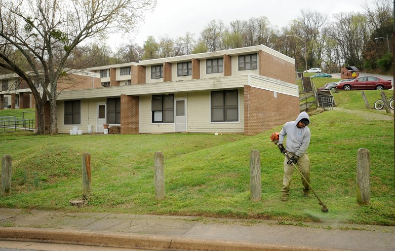 File Photo/NWA Democrat-Gazette/ANDY SHUPE A worker uses a string trimmer March 30 around a fence at the Willow Heights public housing complex west of the Confederate Cemetery in Fayetteville. The property is expected to be sold and residents will be moved to Morgan Manor.
