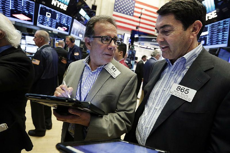 Trader Sal Suarino (left) and Mark Muller work Friday on the fl oor of the New York Stock Exchange.