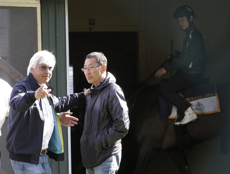 Trainer Bob Baffert, left, appears with Kiyoshi Hagiwara, trainer of race horse Epicharis, passing in background, at Belmont Park, Friday, June 9, 2017, in Elmont, N.Y. Epicharis, is expected to run in the 149th Belmont Stakes horse race on Saturday. 