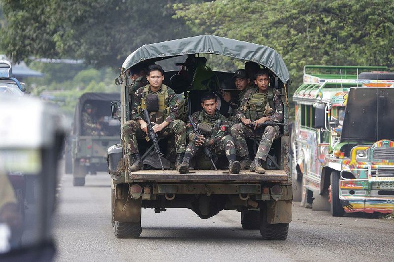 Philippine soldiers move through the outskirts of Marawi on Friday in the battle against Islamic militants. Scores of militants and government troops have died since fighting began nearly three weeks ago.