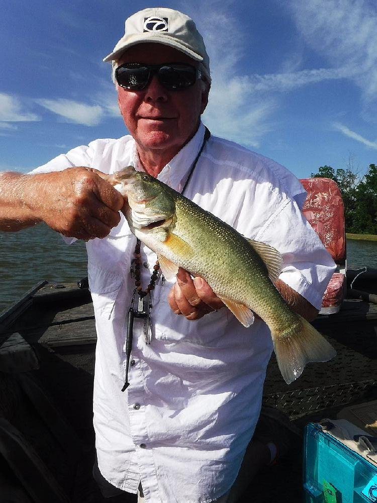 Ray Tucker shows off one of the many bass he caught while fi shing with the author Thursday in a private reservoir near Sherrill.