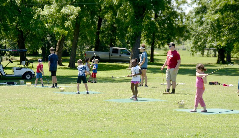 Michael Burchfiel/Siloam Sunday Kids practiced hitting with long irons as part of a fundamental golf camp this week at the Siloam Springs Country Club.