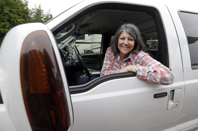 In this photo taken Thursday, June 8, 2017, Nancy Zingheim smiles as she sits in a truck given to her in Chimacum, Wash. Zingheim barely knew Rita Poe when Poe approached her office at the RV park in Washington state, asking for help with her will. Weeks later, the 66-year-old Poe died of colorectal cancer, leaving nearly $800,000 to a dozen national wildlife refuges and parks, mostly in the West. Zingheim, the executor of Poe's estate, went on a 4,000-mile road trip to learn more about the woman who lived in a 27-foot Airstream trailer with her dog and cat, and the wild places that captivated her. 