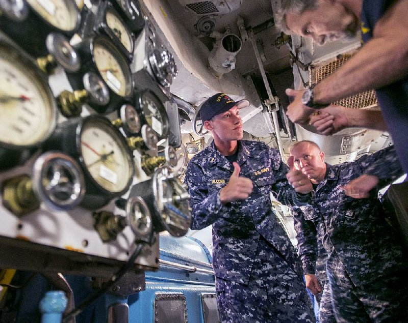 Navy Ensign Brandon Alcorn (left) signals a thumbs-up to Arkansas Inland Maritime Museum staff member Joseph Mathis (right) after powering up the engines of the USS Razorback submarine Monday afternoon in North Little Rock. Fifteen crew members of the Navy’s USS Little Rock are visiting the city that the new warship is named after.