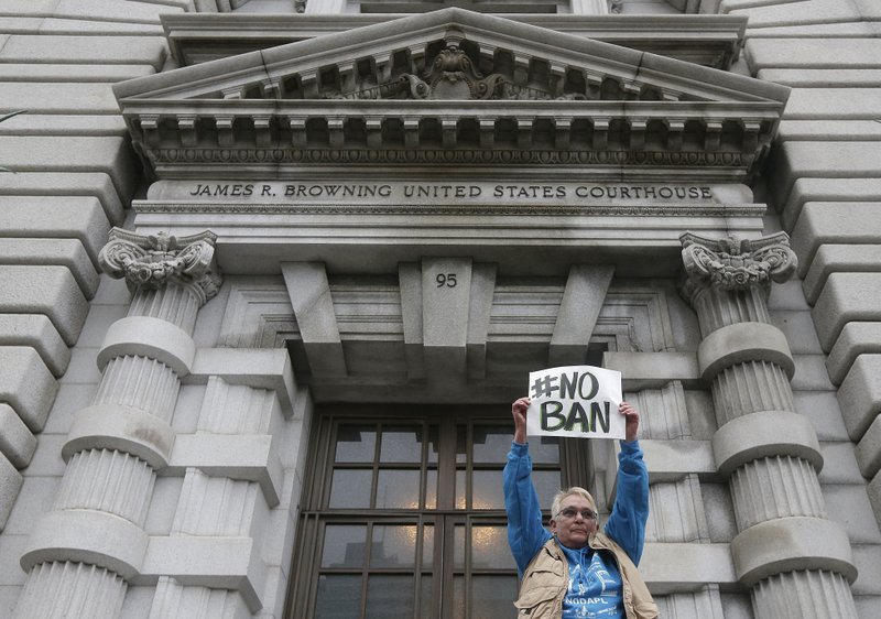 In this Feb. 7, 2017, file photo, Karen Shore holds up a sign outside of the 9th U.S. Circuit Court of Appeals in San Francisco, Calif. A ruling Monday, June 12, 2017, from a unanimous three-judge panel of the 9th U.S. Circuit Court of Appeals deals the administration another legal defeat as the Supreme Court considers a separate case on the issue. 