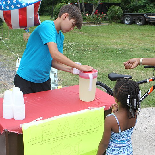 The Sentinel-Record/Richard Rasmussen HARD AT WORK: Kaleb Hayes, 14, serves some lemonade to Syncere Burton, 4, Monday at his lemonade stand outside his home in the 300 block of Woodlawn Avenue. Hayes was selling lemonade to raise money to buy a bicycle on Thursday, which prompted an outpouring from the local community, resulting in two bicycles being given to him.