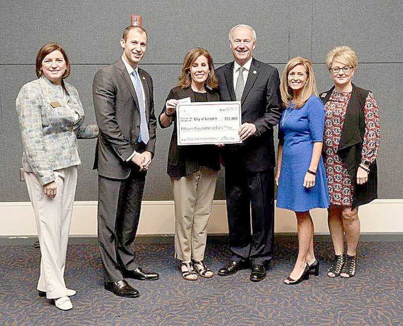 SUBMITTED PHOTO Arkansas Gov. Asa Hutchinson presents a $15,000 rural community grant to Rhonda Hulse, business manager for Lincoln. The grant will be used to purchase 12 sets of turnout gear for Lincoln Fire Department. The money was received through the Arkansas Rural Community Grant Program. Others at the presentation were Jamie Pafford-Gresham, Mike Preston, Amy Fecher and Lynn Hawkins, representing Arkansas Rural Development Commission and Arkansas Economic Development Commission.