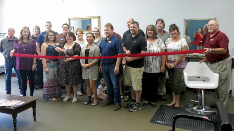 Photo by Susan Holland Hilarie Dodd, owner of the new Hair Thairapy Salon in Gravette, prepared to cut the ribbon at her shop Tuesday, June 6. She was joined at the ribbon cutting by Gravette mayor Kurt Maddox, city finance director Carl Rabey and several members of the Greater Gravette Chamber of Commerce.