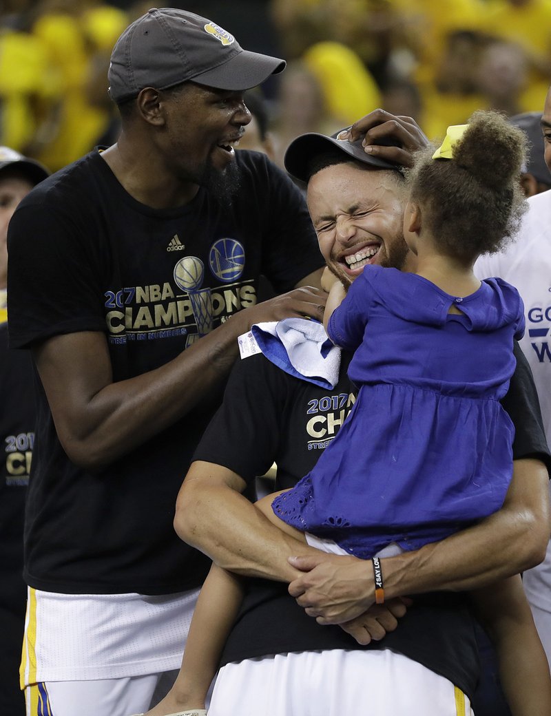 Golden State Warriors guard Stephen Curry, center, holds his daughter Riley as they celebrate with forward Kevin Durant, left, after Game 5 of basketball's NBA Finals against the Cleveland Cavaliers in Oakland, Calif., Monday, June 12, 2017. The Warriors won 129-120 to win the NBA championship. (AP Photo/Marcio Jose Sanchez)